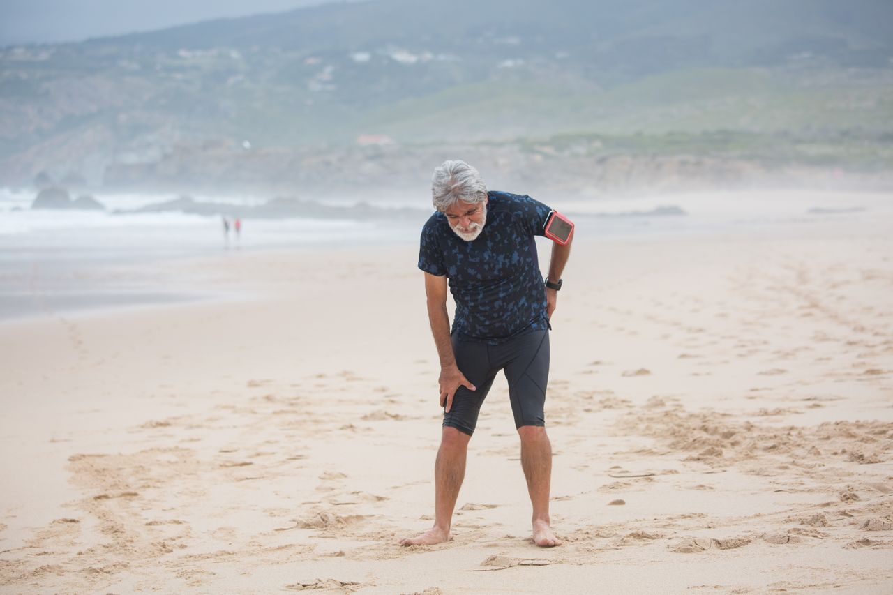 Elderly man stretching on a sandy beach
