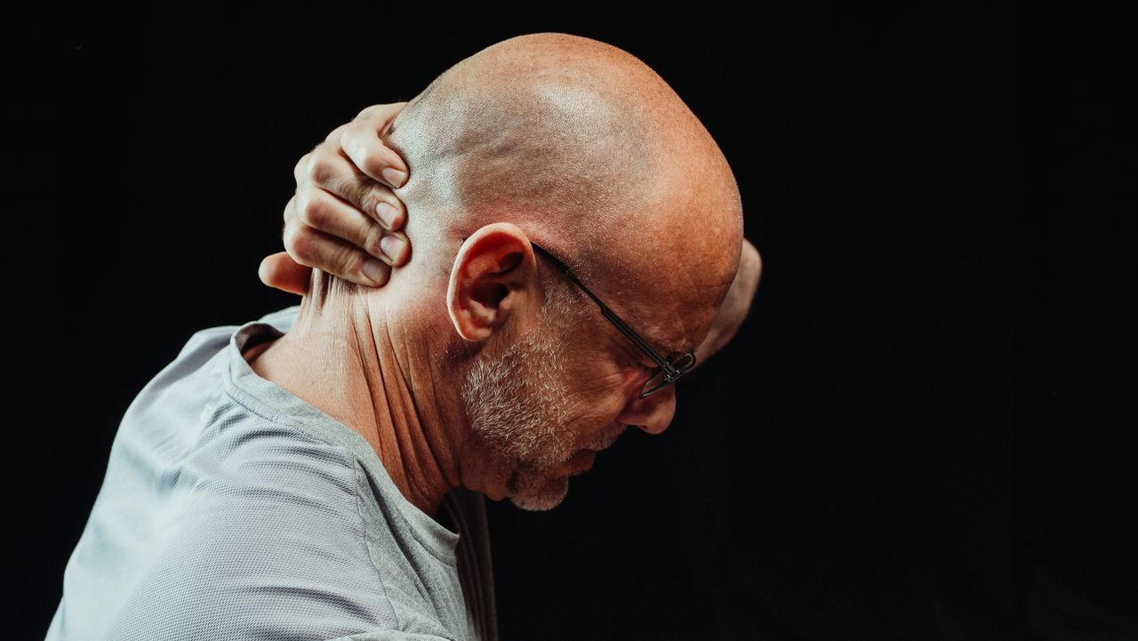 A man holding his back neck due to pain